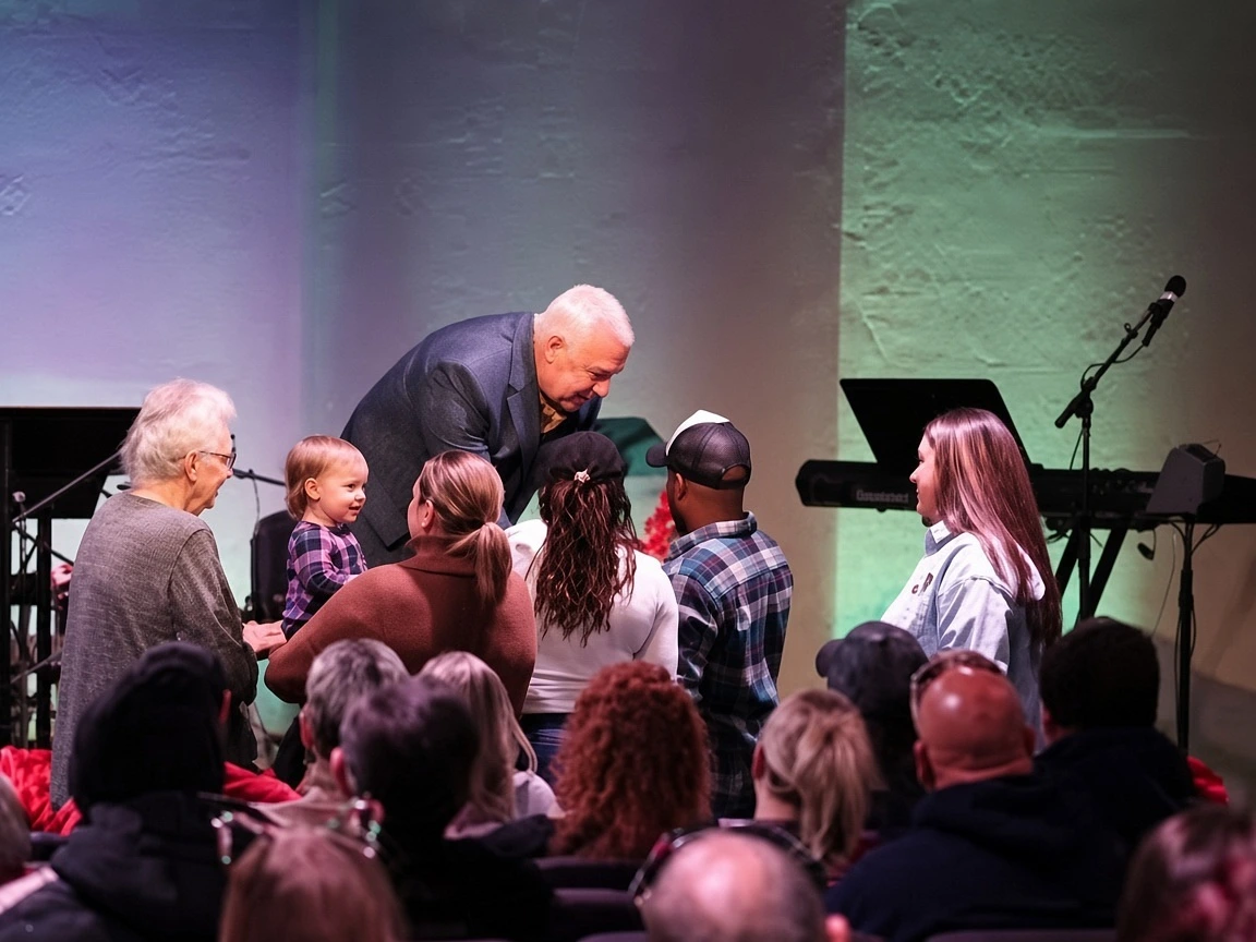 A pastor leaning down to greet a toddler and family during a gathering at The Refuge.